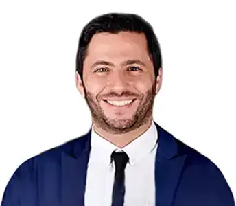 Sonriente profesional en formación en odontología, usando traje azul y corbata, en un entorno académico de Campus Odontológico, centro de excelencia en educación odontológica.