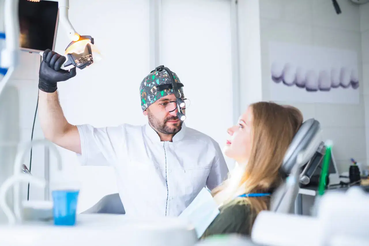 Dentista mostrando equipo dental a paciente en clínica odontológica moderna, con equipo avanzado y ambiente profesional.